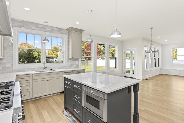 kitchen with sink, gray cabinetry, a kitchen island, pendant lighting, and stainless steel appliances