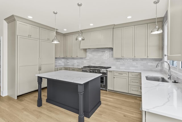 kitchen featuring pendant lighting, sink, high end stainless steel range oven, a center island, and light stone counters