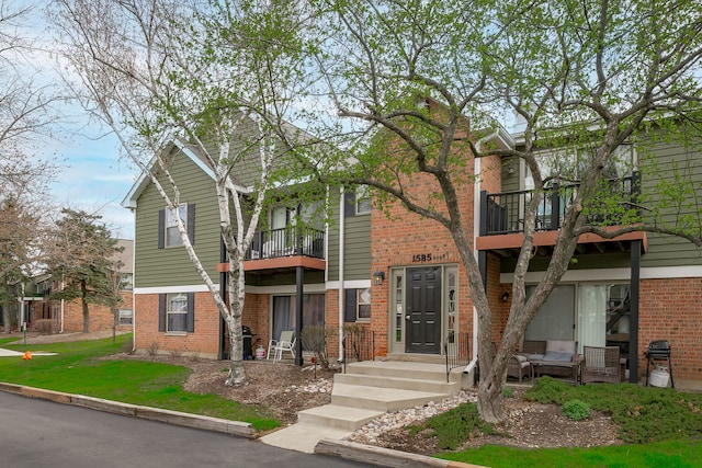view of front of home featuring a balcony and brick siding