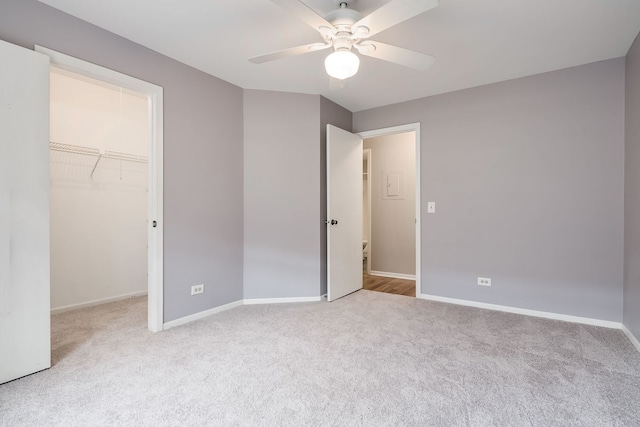 unfurnished bedroom with a walk in closet, baseboards, and carpet