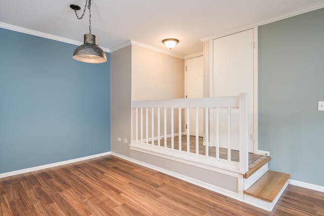 unfurnished room with wood finished floors, baseboards, and ornamental molding