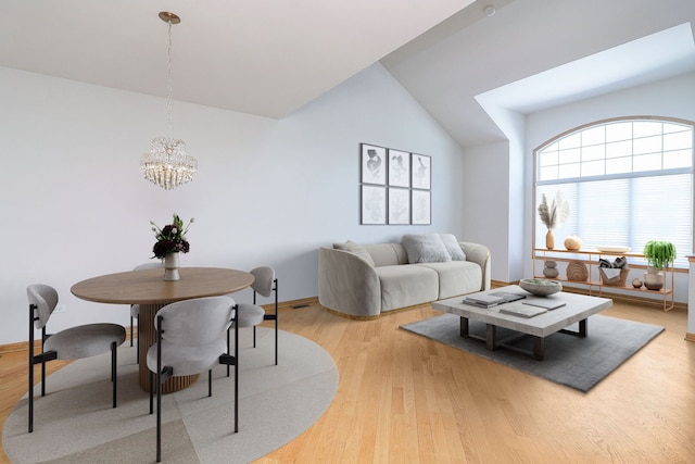 dining space with lofted ceiling, an inviting chandelier, light wood-style flooring, and baseboards