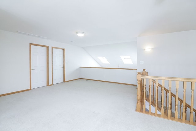 additional living space with vaulted ceiling with skylight, carpet floors, and baseboards