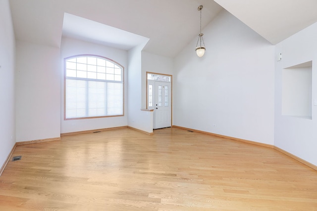 empty room with light wood-style floors, visible vents, and baseboards