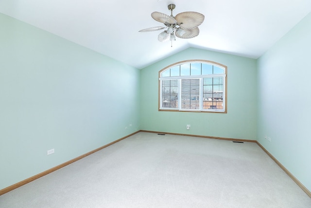 empty room featuring vaulted ceiling, carpet floors, visible vents, and a ceiling fan