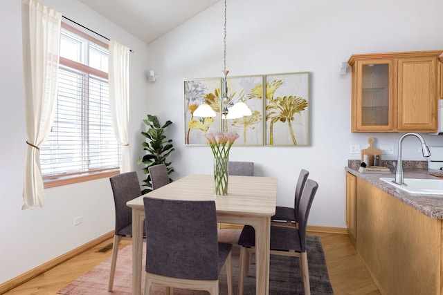 dining room featuring plenty of natural light, vaulted ceiling, a notable chandelier, and light wood-style flooring