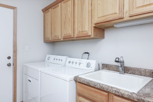 clothes washing area with washing machine and dryer, cabinet space, and a sink