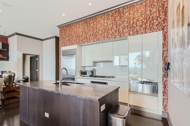 kitchen with sink, crown molding, white cabinetry, stainless steel appliances, and a center island with sink