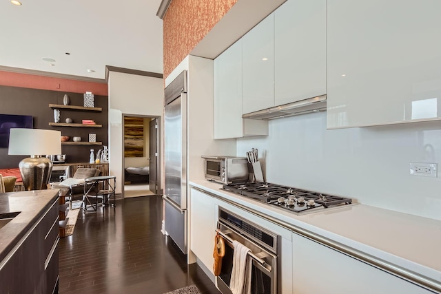 kitchen with dark wood-type flooring, stainless steel appliances, and white cabinets