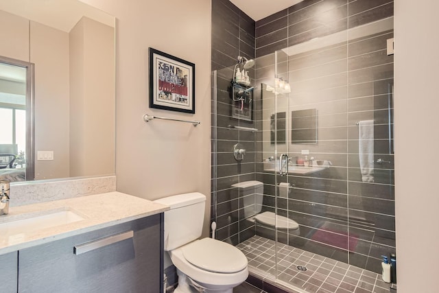 bathroom featuring vanity, a shower with shower door, and toilet