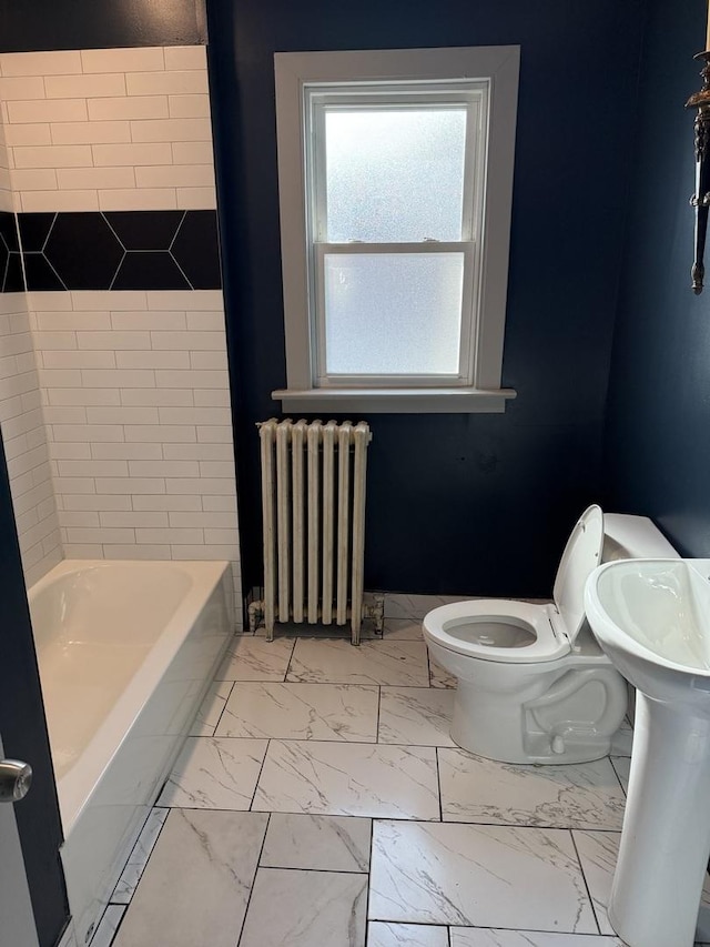 bathroom with a tub to relax in, toilet, and radiator