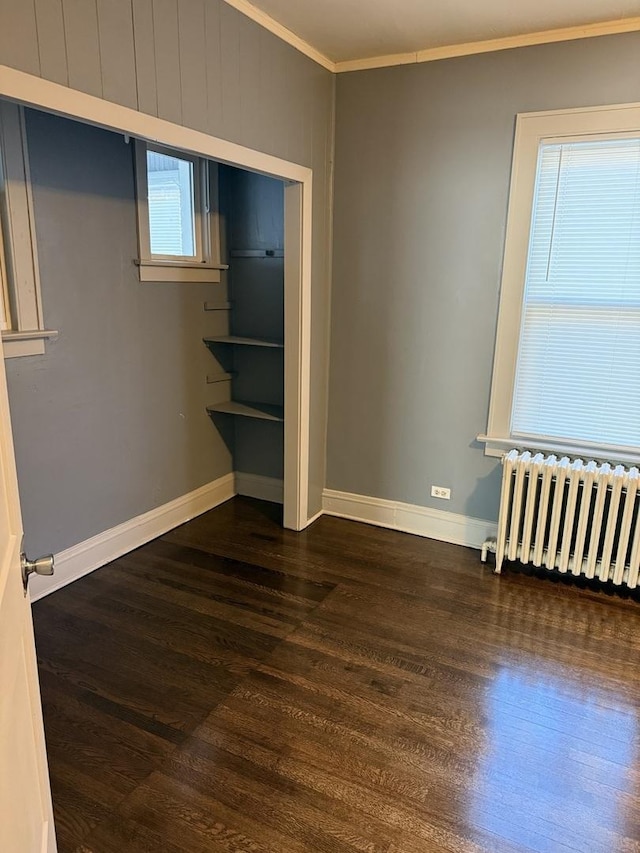 unfurnished bedroom with dark hardwood / wood-style flooring, crown molding, and radiator heating unit