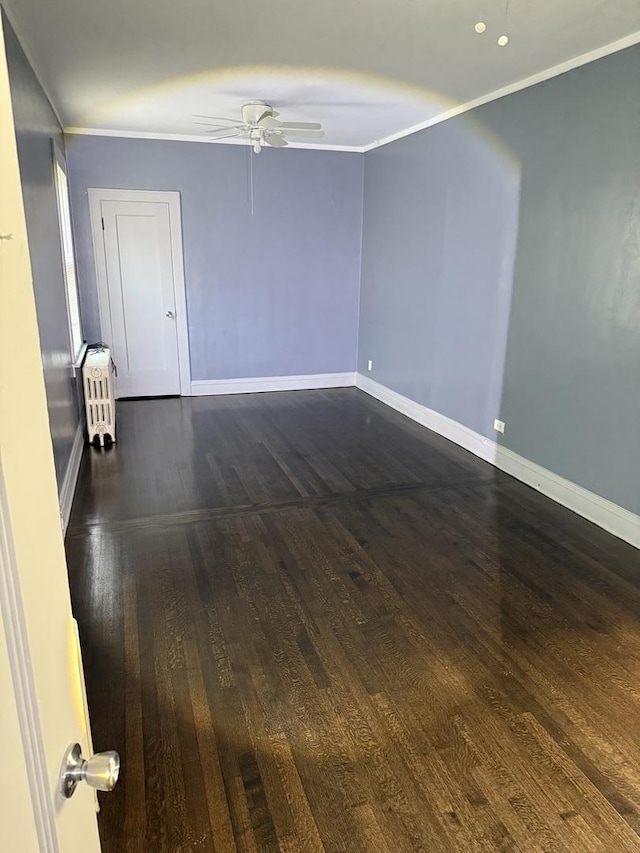 spare room with crown molding, dark wood-type flooring, radiator heating unit, and ceiling fan