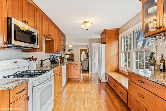 kitchen featuring sink, light stone counters, white appliances, and light hardwood / wood-style flooring