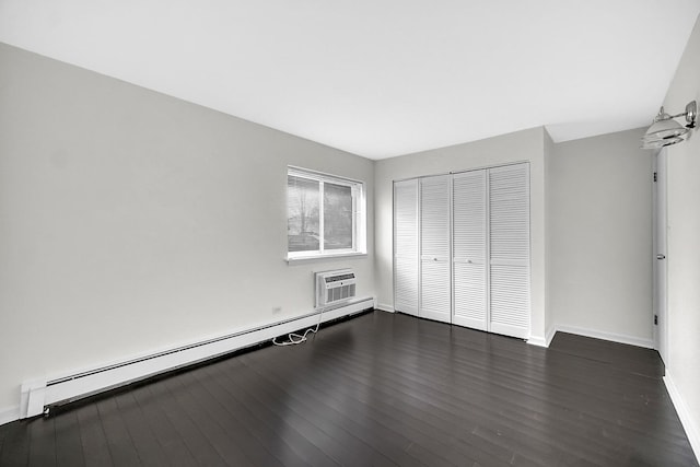 unfurnished bedroom featuring an AC wall unit, dark wood-type flooring, a closet, and baseboard heating