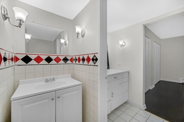 bathroom with a baseboard radiator, vanity, tile patterned flooring, and tile walls