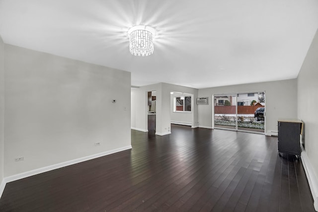 unfurnished living room with dark hardwood / wood-style flooring, a baseboard radiator, a wall unit AC, and an inviting chandelier