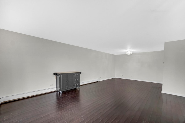 spare room featuring dark wood-type flooring and a baseboard heating unit