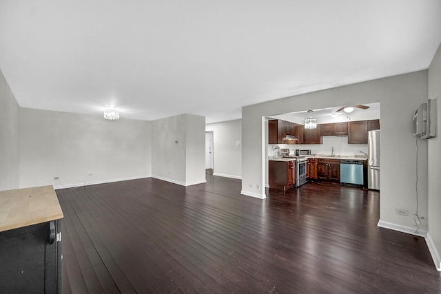 unfurnished living room featuring ceiling fan, sink, and dark hardwood / wood-style flooring