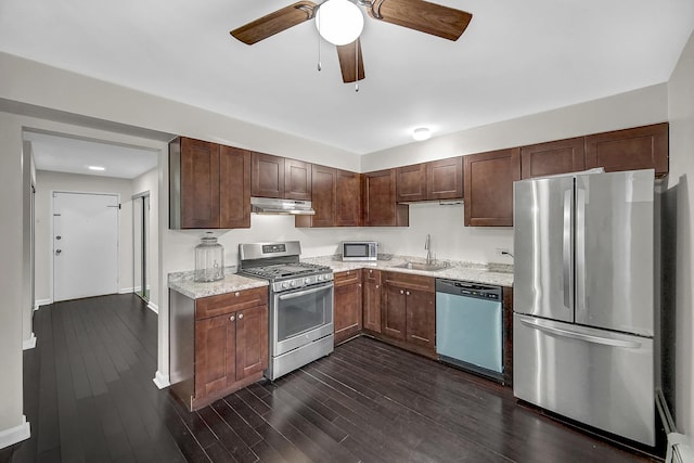 kitchen featuring sink, dark wood-type flooring, light stone counters, stainless steel appliances, and dark brown cabinets