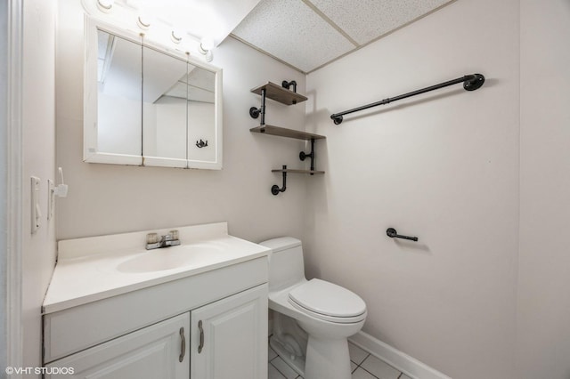 bathroom featuring tile patterned floors, toilet, vanity, and a drop ceiling