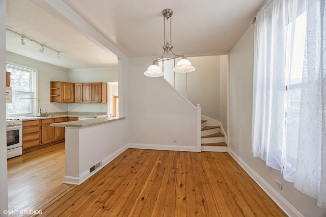 kitchen featuring sink, decorative light fixtures, kitchen peninsula, light hardwood / wood-style floors, and white range oven