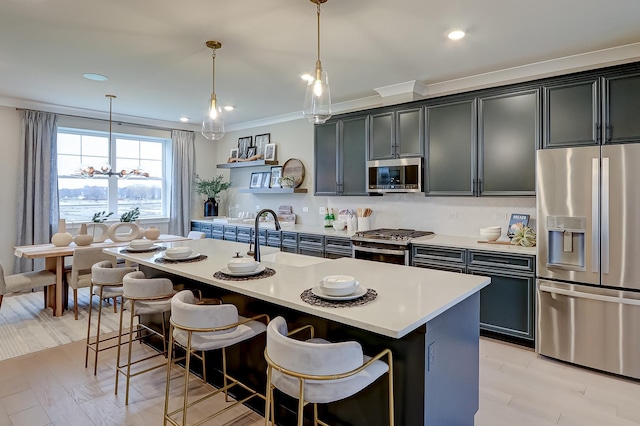 kitchen with pendant lighting, sink, appliances with stainless steel finishes, a center island with sink, and a kitchen bar