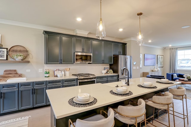 kitchen featuring sink, a kitchen breakfast bar, hanging light fixtures, stainless steel appliances, and a center island with sink