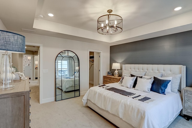 carpeted bedroom with a raised ceiling, a spacious closet, an inviting chandelier, and a closet