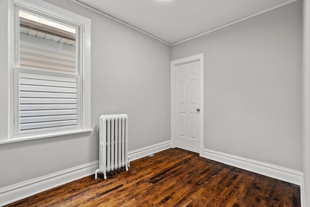 spare room featuring crown molding, dark hardwood / wood-style flooring, and radiator