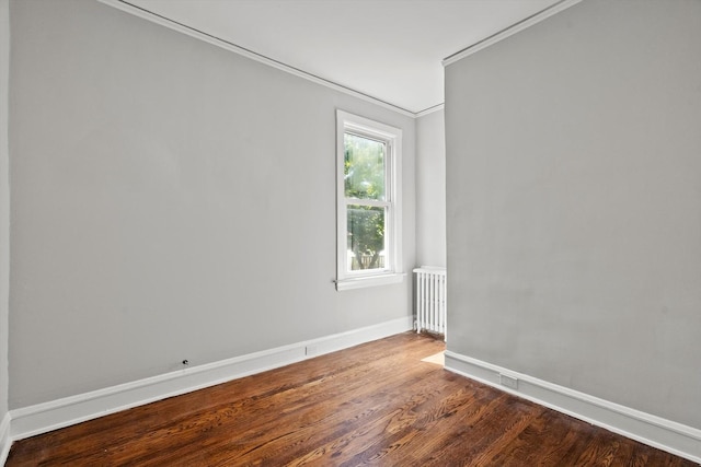 empty room with crown molding, radiator, and hardwood / wood-style flooring