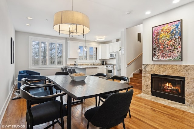 dining space featuring light wood-style flooring, visible vents, stairway, and baseboards