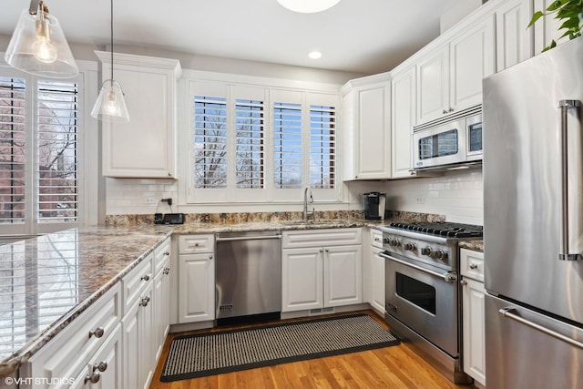 kitchen featuring white cabinetry, appliances with stainless steel finishes, light wood-style flooring, and a sink