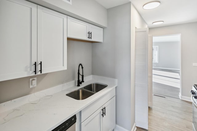 kitchen with white cabinetry, sink, light stone counters, and light hardwood / wood-style floors