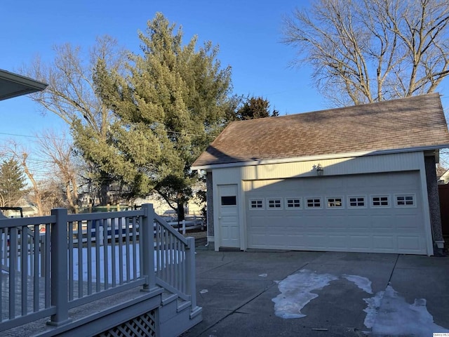 view of home's exterior featuring a garage, a wooden deck, and an outbuilding