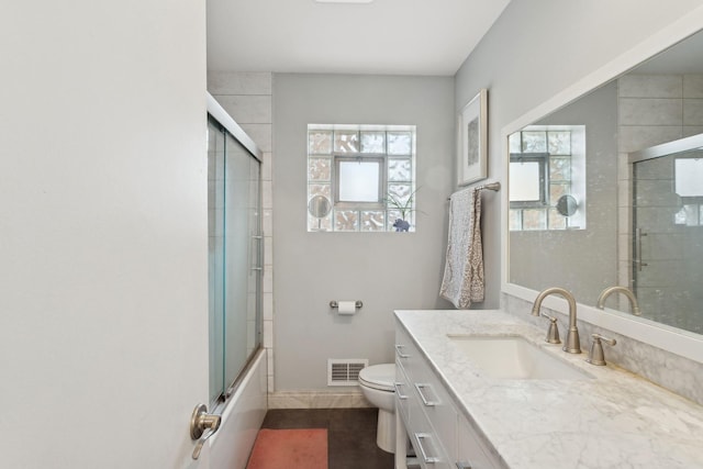 full bathroom featuring vanity, tile patterned floors, shower / bath combination with glass door, and toilet