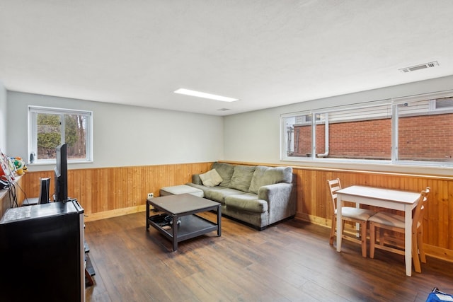 living room with dark hardwood / wood-style flooring, a wood stove, and wood walls