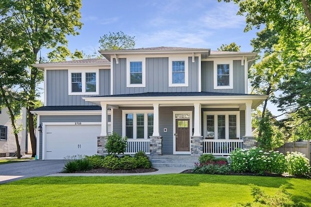 view of front of property with a garage, covered porch, and a front lawn