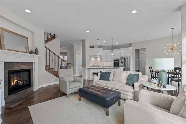 living room with a chandelier, dark hardwood / wood-style flooring, and a tiled fireplace