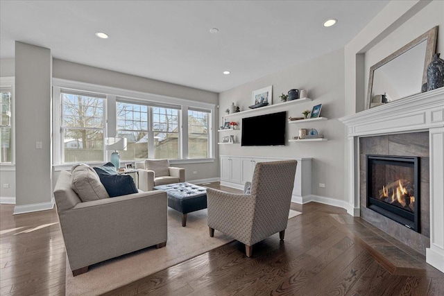 living room with dark wood-type flooring, a tiled fireplace, and built in features