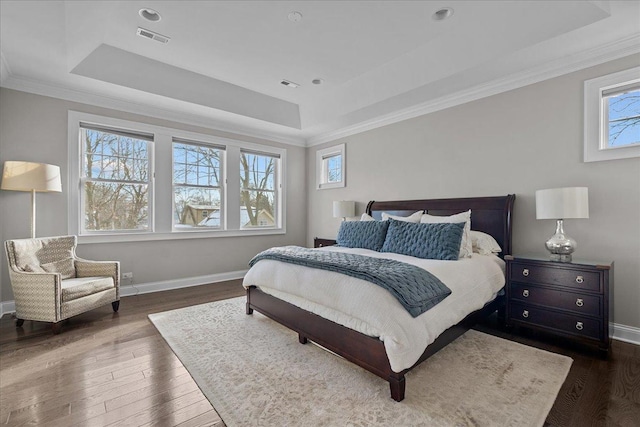 bedroom with ornamental molding, dark wood-type flooring, and a tray ceiling