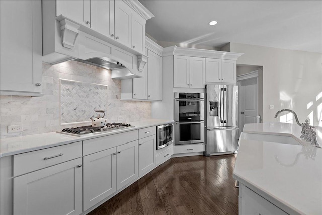 kitchen with stainless steel appliances, sink, white cabinets, and backsplash