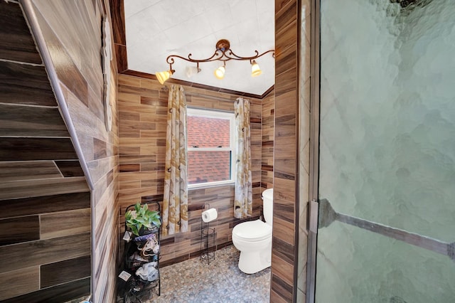 bathroom featuring toilet, an enclosed shower, and wood walls