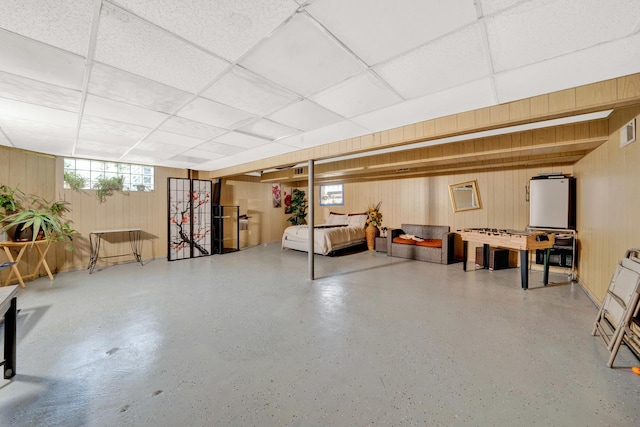 basement featuring wooden walls and a drop ceiling