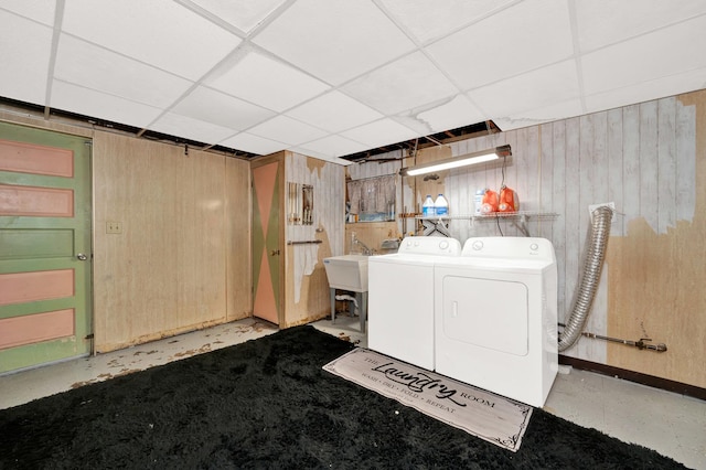 laundry room with sink, washer and clothes dryer, and wood walls