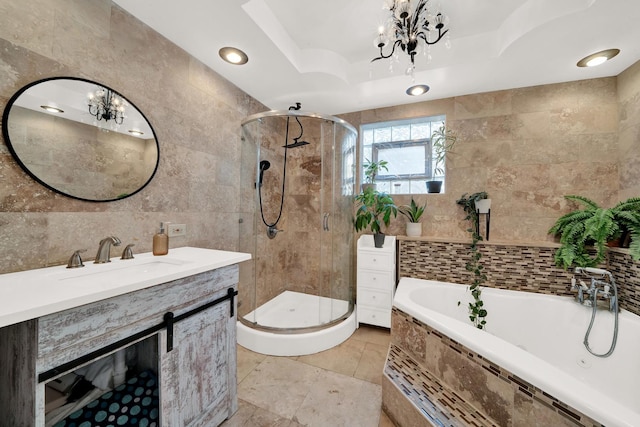 bathroom with vanity, a tray ceiling, plus walk in shower, and tile walls