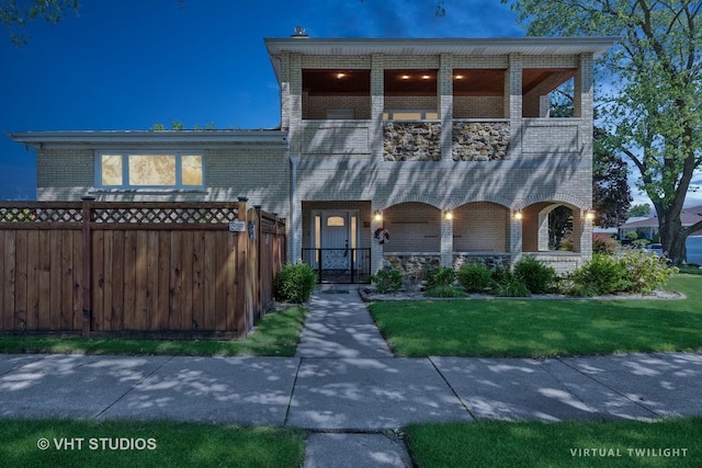 view of front of home featuring a balcony and a front yard