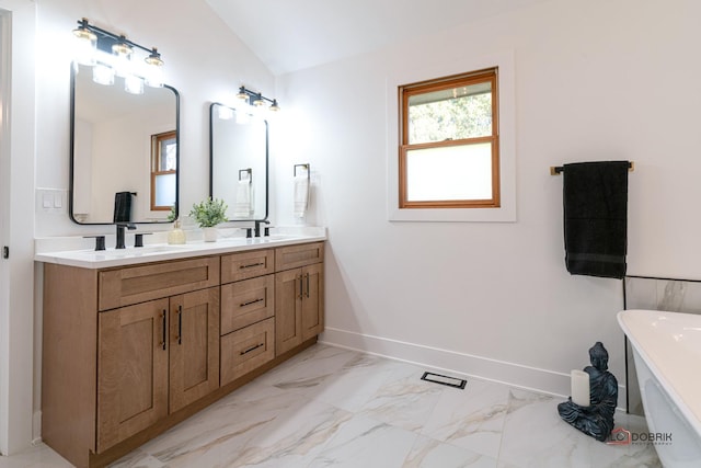 bathroom featuring vaulted ceiling, a bathing tub, and vanity