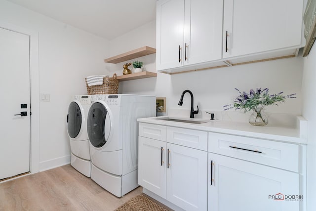 clothes washing area featuring cabinets, washer and dryer, sink, and light wood-type flooring