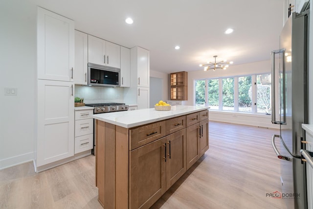 kitchen with appliances with stainless steel finishes, tasteful backsplash, white cabinetry, a center island, and light stone countertops